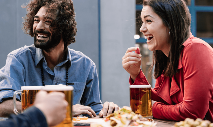 group of friends laughing together over some food and beers