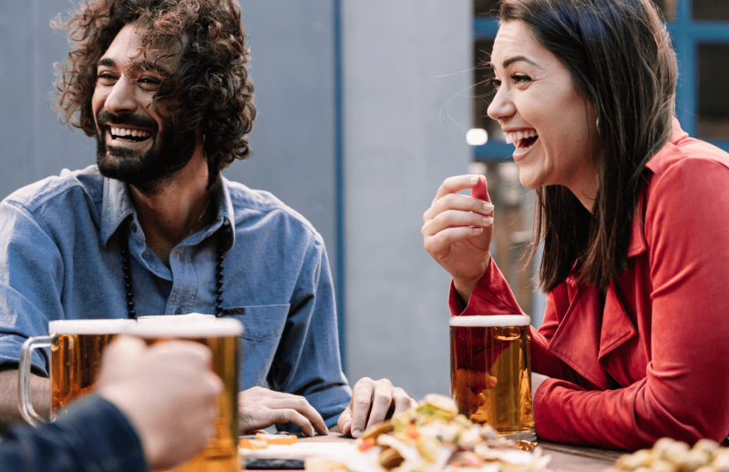 group of friends laughing together over some food and beers